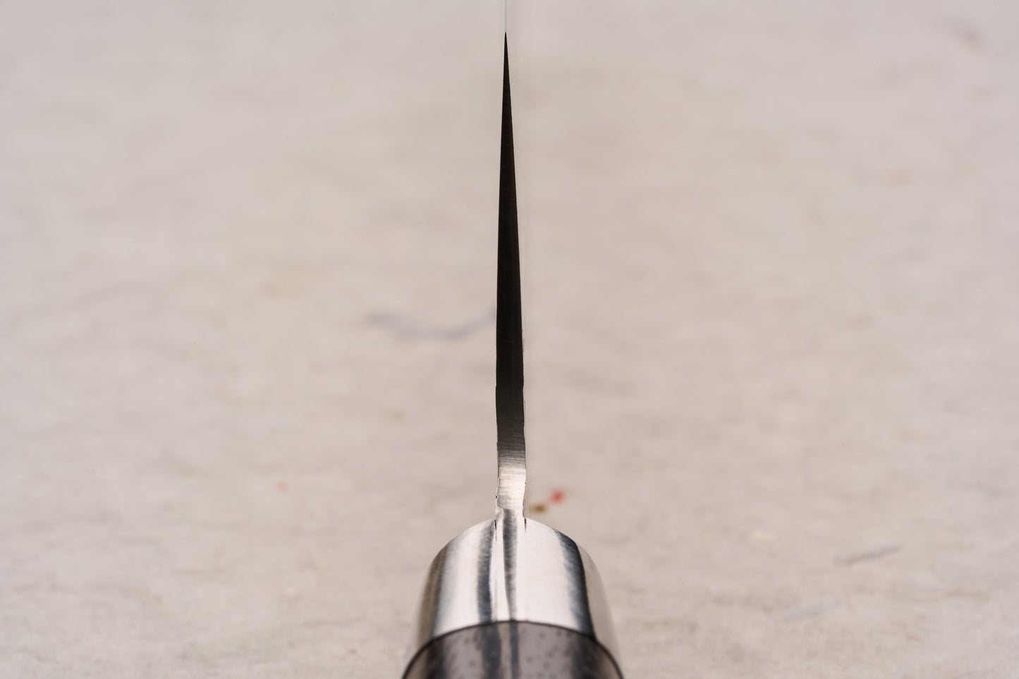 Sakai Takayuki SG2 Tsuchime Damascus Western Kengata Gyuto 190mm viewed edge-on, highlighting its precision-crafted blade rising from the handle, exemplifying Japanese craftsmanship and versatile design for kitchen enthusiasts.