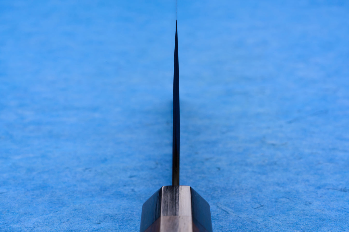 Shibata Koutetsu Chromax Migaki Boss Nakiri 170mm knife stands upright, showcasing its thin blade and wooden handle against a textured background, ideal for slicing, dicing, and mincing.