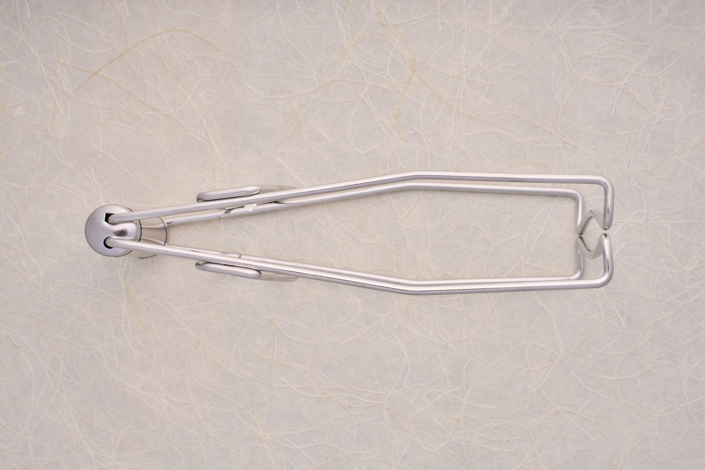 Shimoyama Stainless Steel Dish Clip Lifter, a sleek, wall-mounted, fold-out towel holder against a textured wall, exemplifying functional elegance in kitchen accessories.