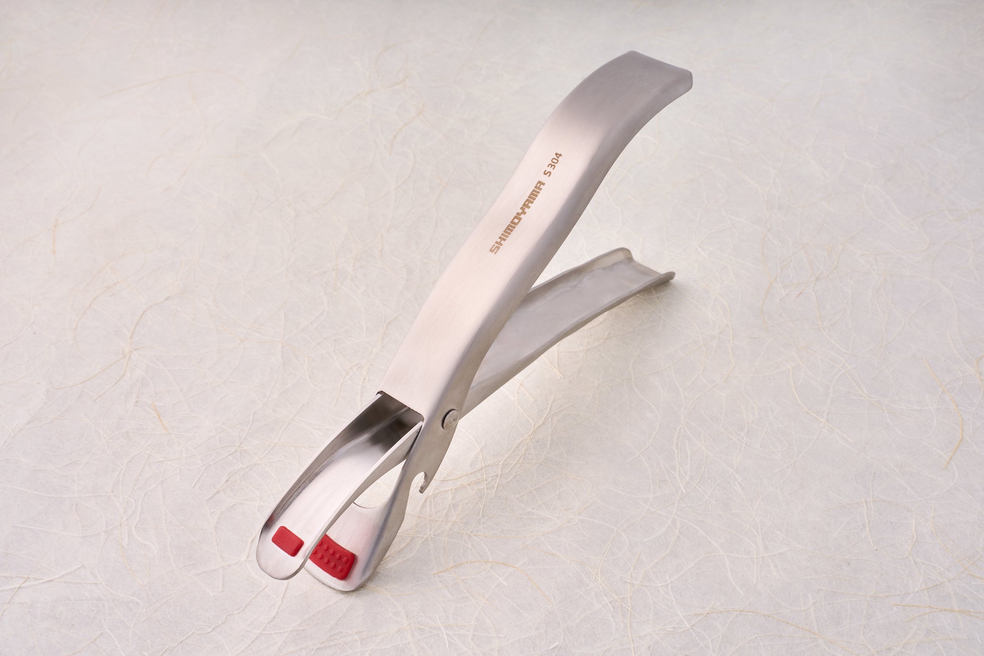 Shimoyama Stainless Steel Bowl Clip with red silicone grip pads, ideal for serving or grilling, reflecting Knifewear's dedication to quality chef tools.