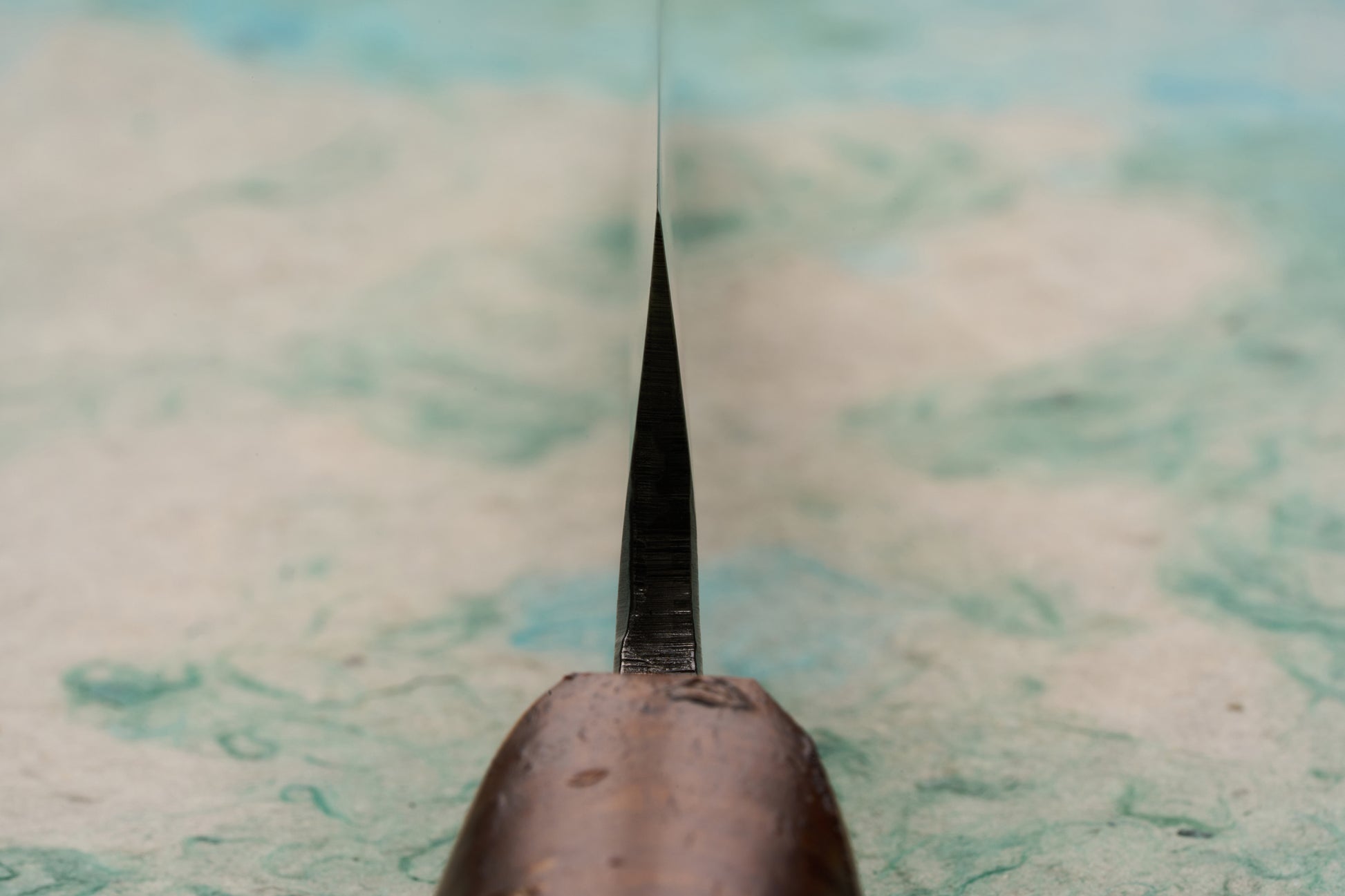 Tottori Otsuka Hamono Aoichi Yamagoya Petty 125mm, featuring a thin, wickedly sharp metal blade rising vertically from a polished cherrywood handle, designed for precision tasks on a cutting board.