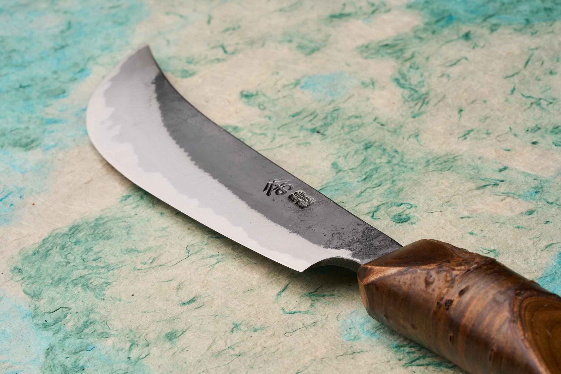 Tottori Otsuka Hamono Aoichi Samurai Knife 180mm features a hamon-lined blade with kanji maker’s mark and a polished cherrywood handle, showcasing masterful craftsmanship in Japanese kitchen knives.