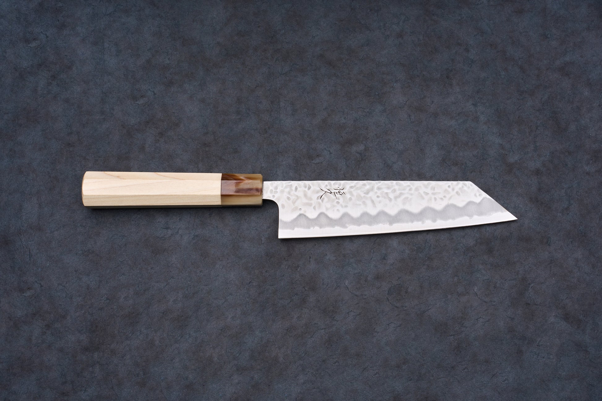 Tsunehisa Shiroichi Stainless Nijuhachi 廿捌 Tsuchime Bunka 165mm knife, featuring a hammered blade and octagonal wood handle, on a dark surface.