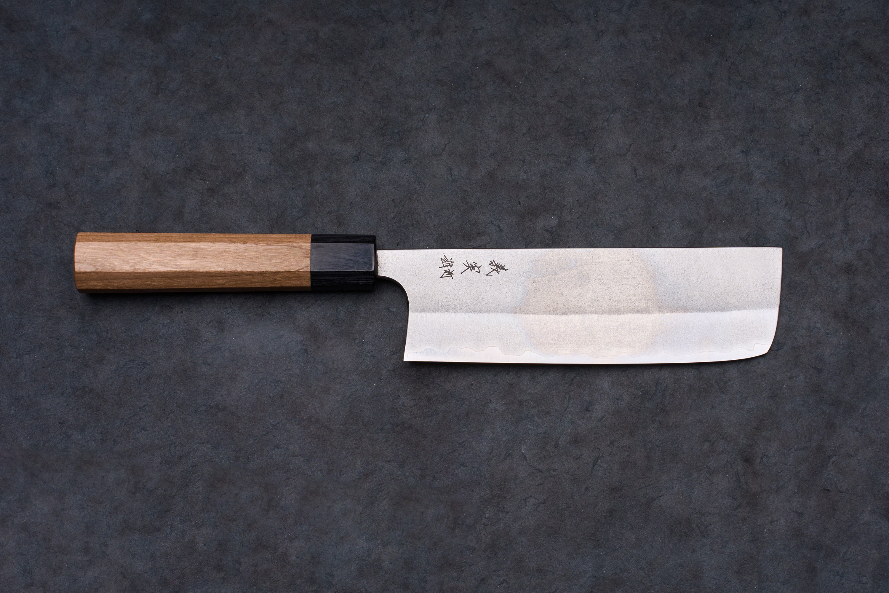 Yoshimi Kato AS/S Nashiji Nakiri 165mm knife with a stainless-steel blade, kanji engraving, and octagonal wooden handle on a dark surface.