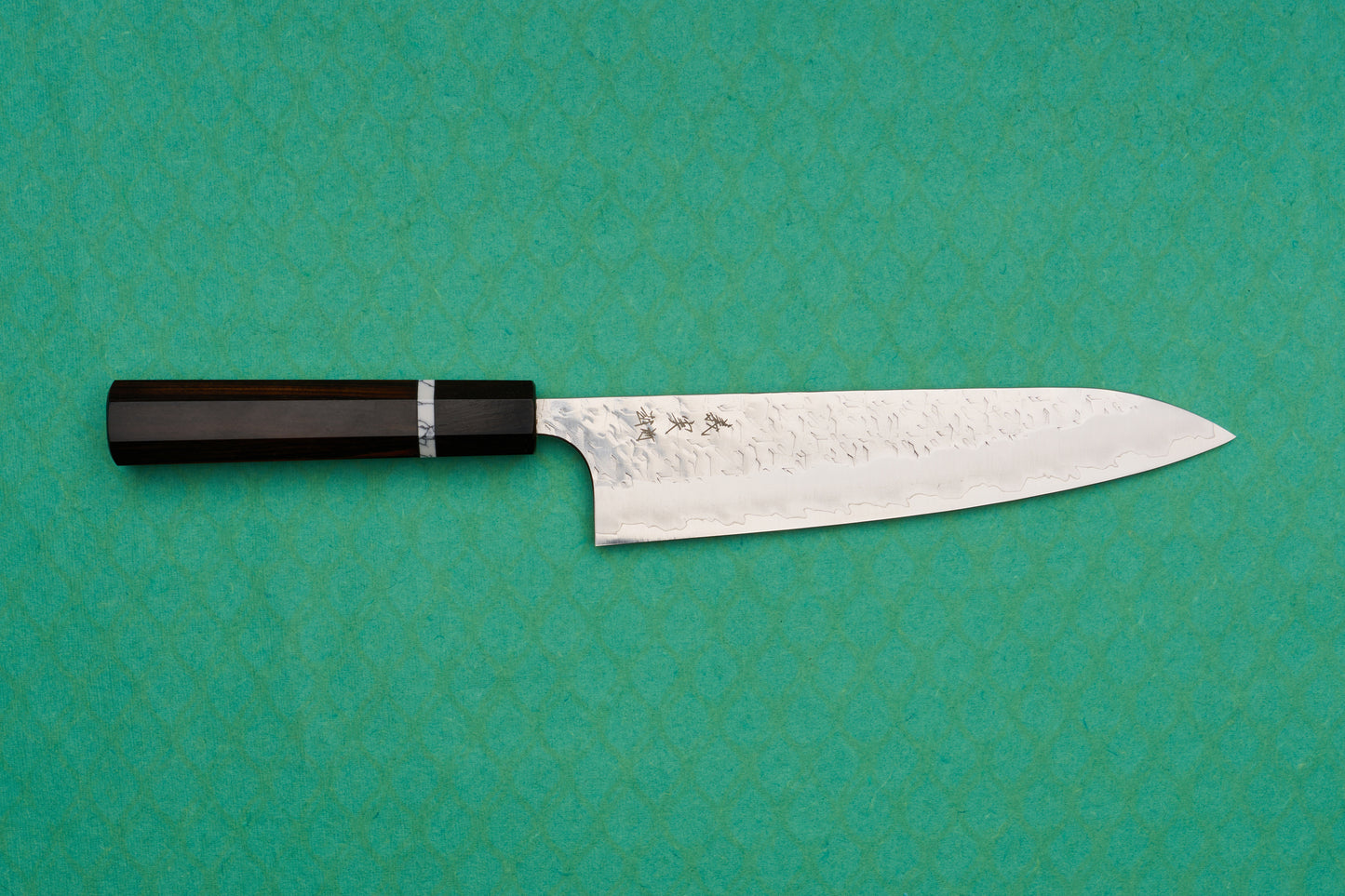 Yoshimi Kato SG2 Hyo Gyuto 210mm features a hand-hammered blade with kanji engraving and a dark octagonal handle, ideal for versatile culinary tasks, reflecting Japanese craftsmanship excellence.